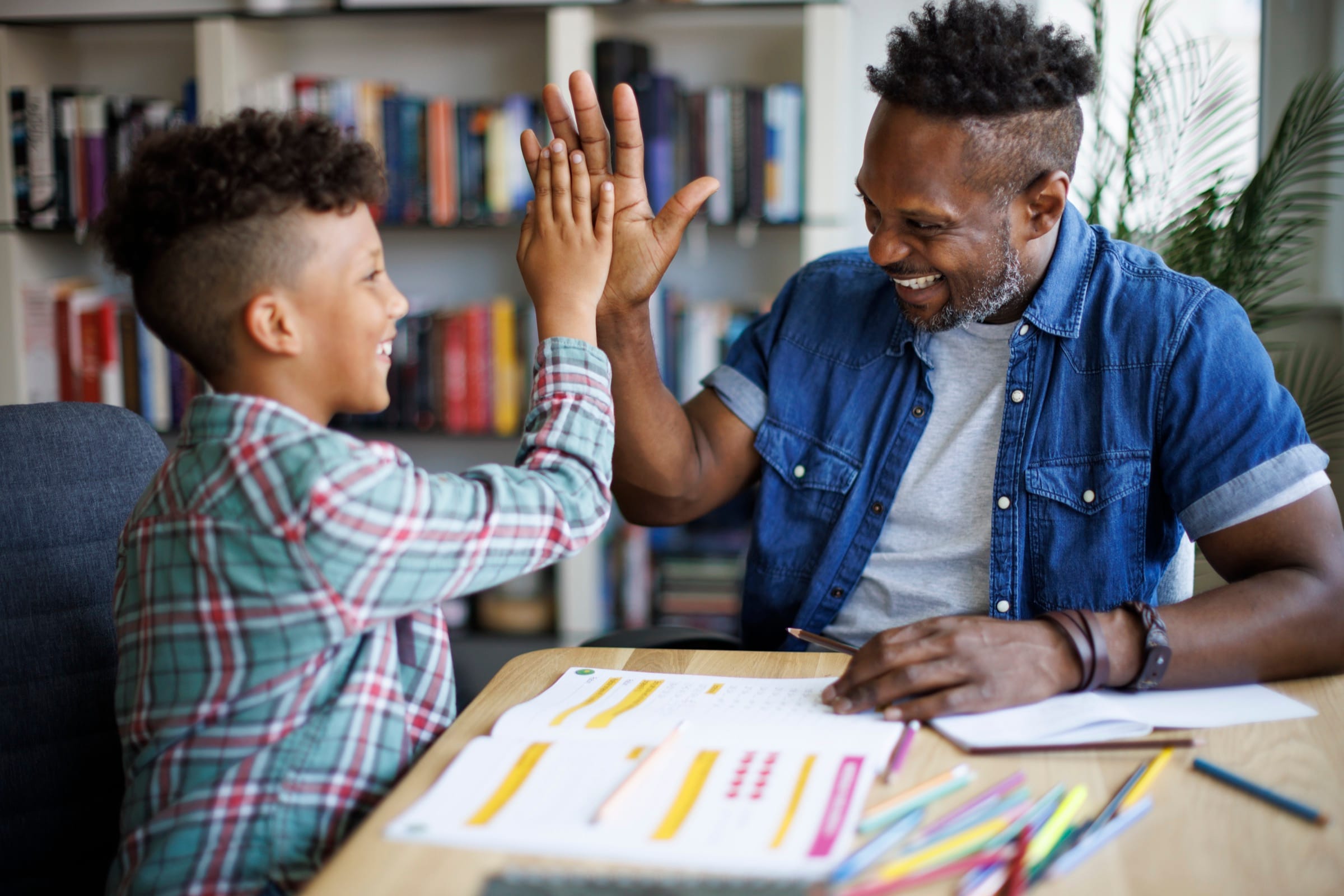 Lehrkraft und Schüler geben sich nach einer erfolgreichen Nachhilfestunde ein High-Five